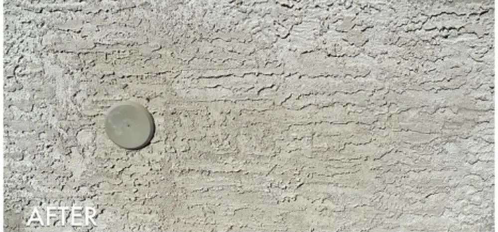 The same wall closed up and refinished, the heavy horizontal drag texture carried across the patched area, with a flush grey clean-out cap set into it.